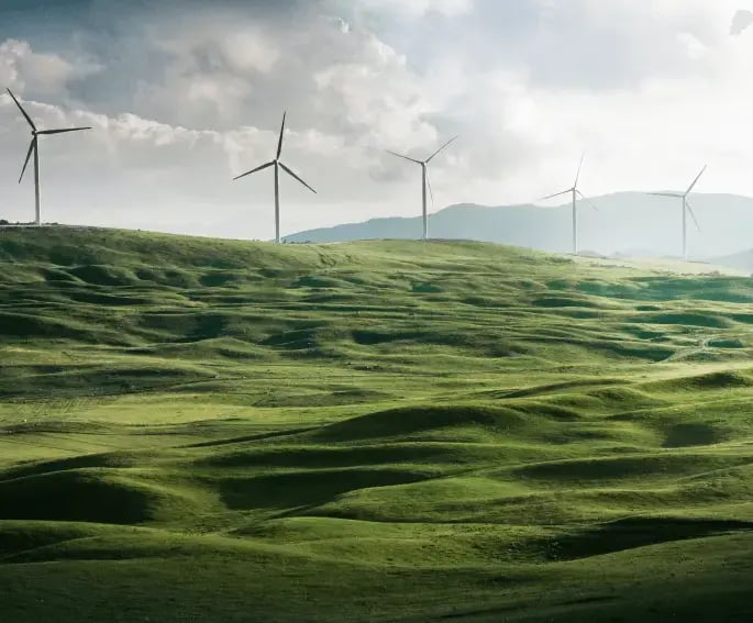 Several wind turbines on rolling green hills under a cloudy sky