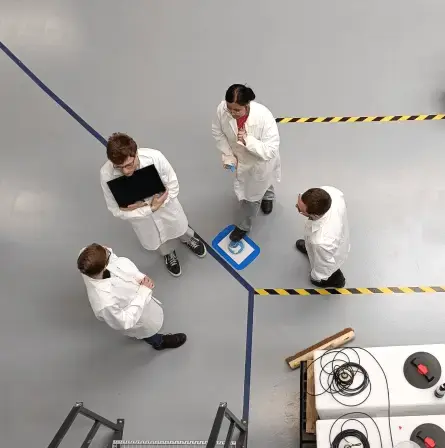 A birds-eye view of four people wearing lab coats, standing in together in a lab environment