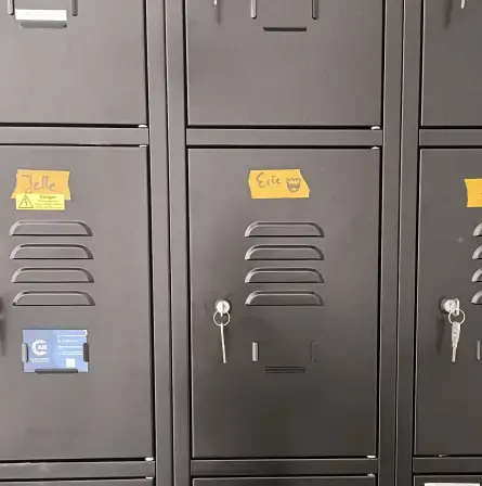 A close-up view of dark grey metal storage lockers with orange name labels.